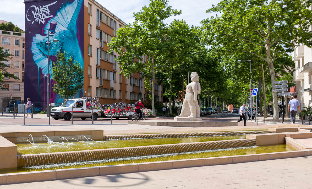 Fontaine bassin déversoir avec chute crénelée sur la place des Tapis